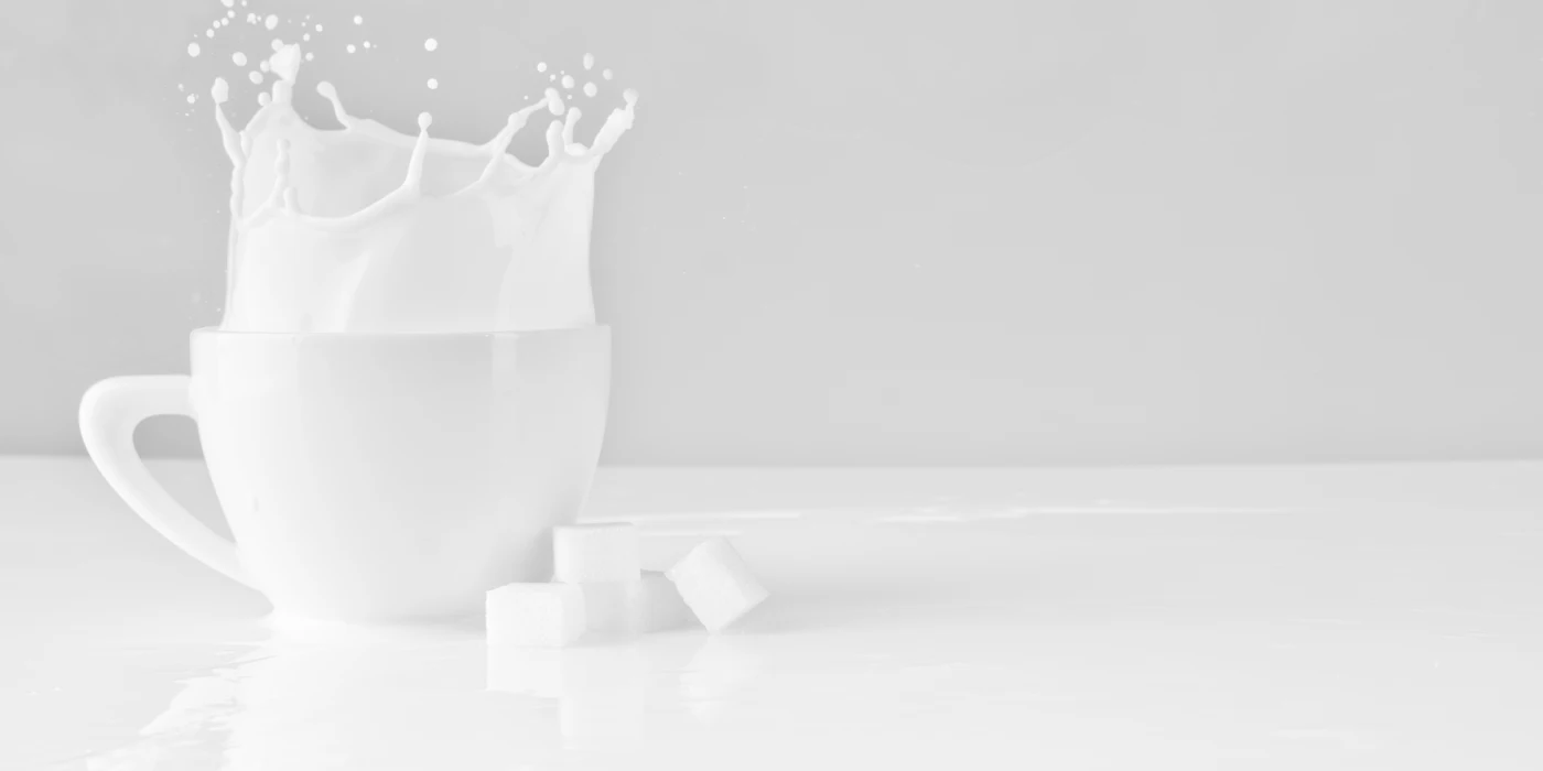 A sugar cube splashing into a white cup of milk