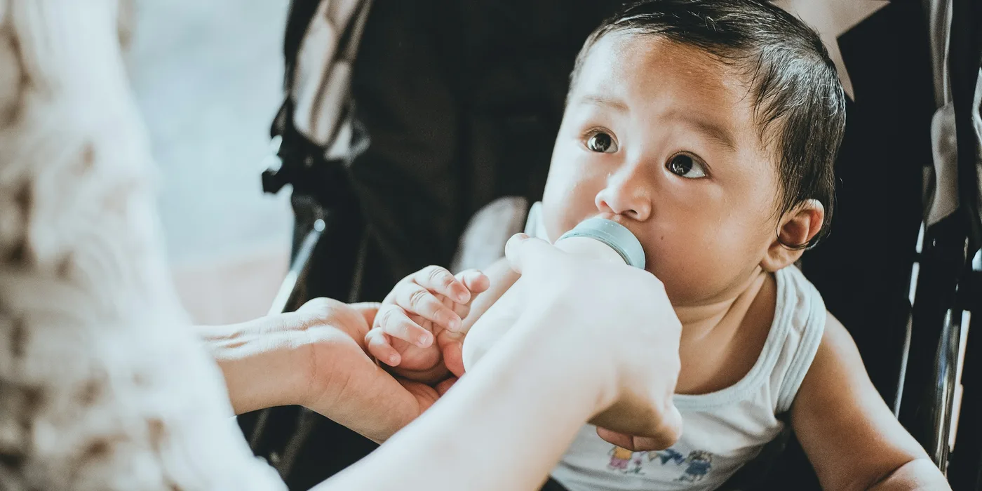 A parent feeding a baby from a bottle