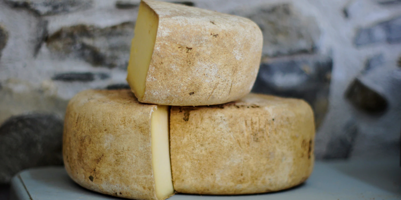 Wheels of aged cheese cut and stacked on a wooden board