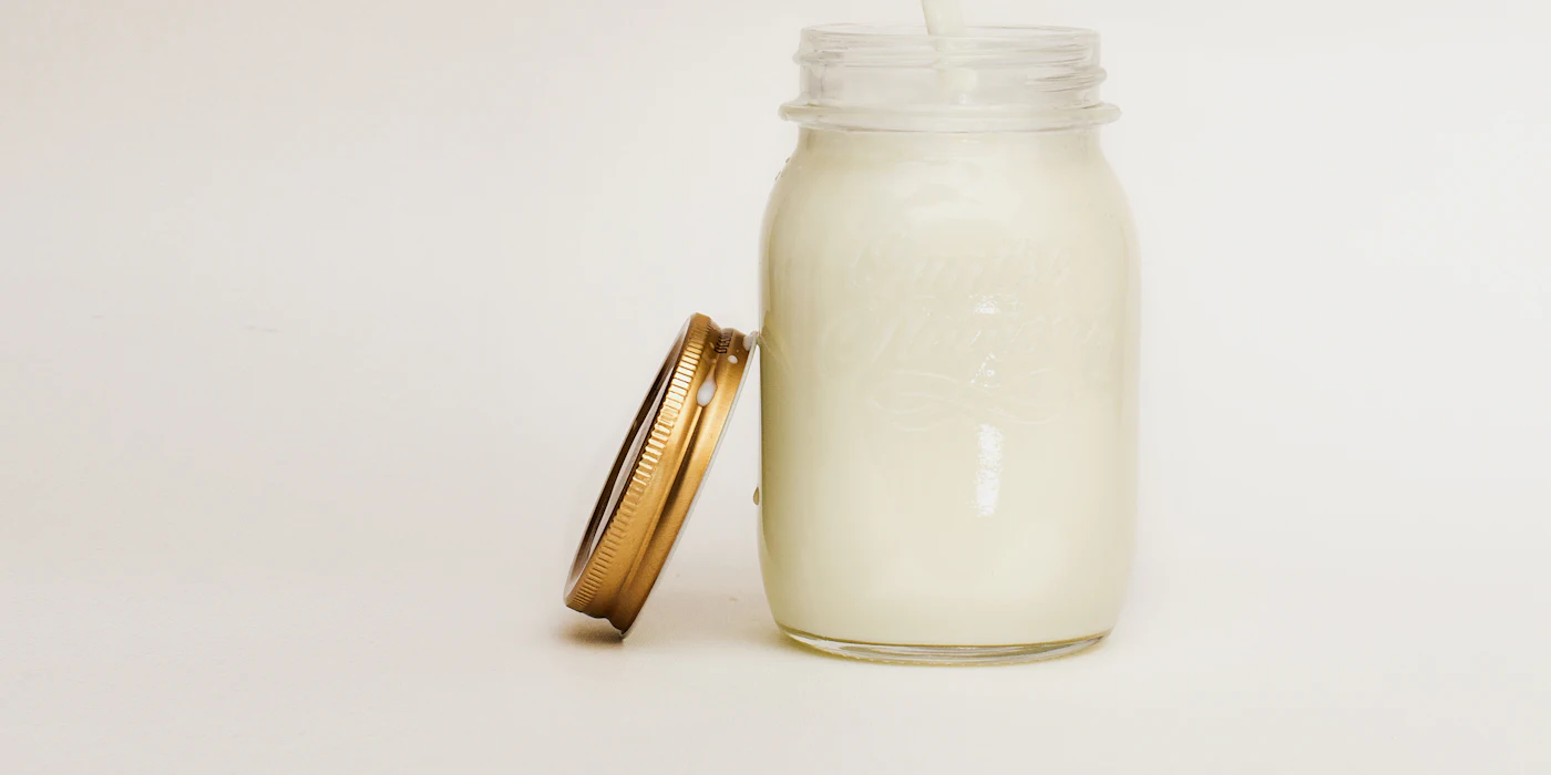 Milk being poured into a glass mason jar