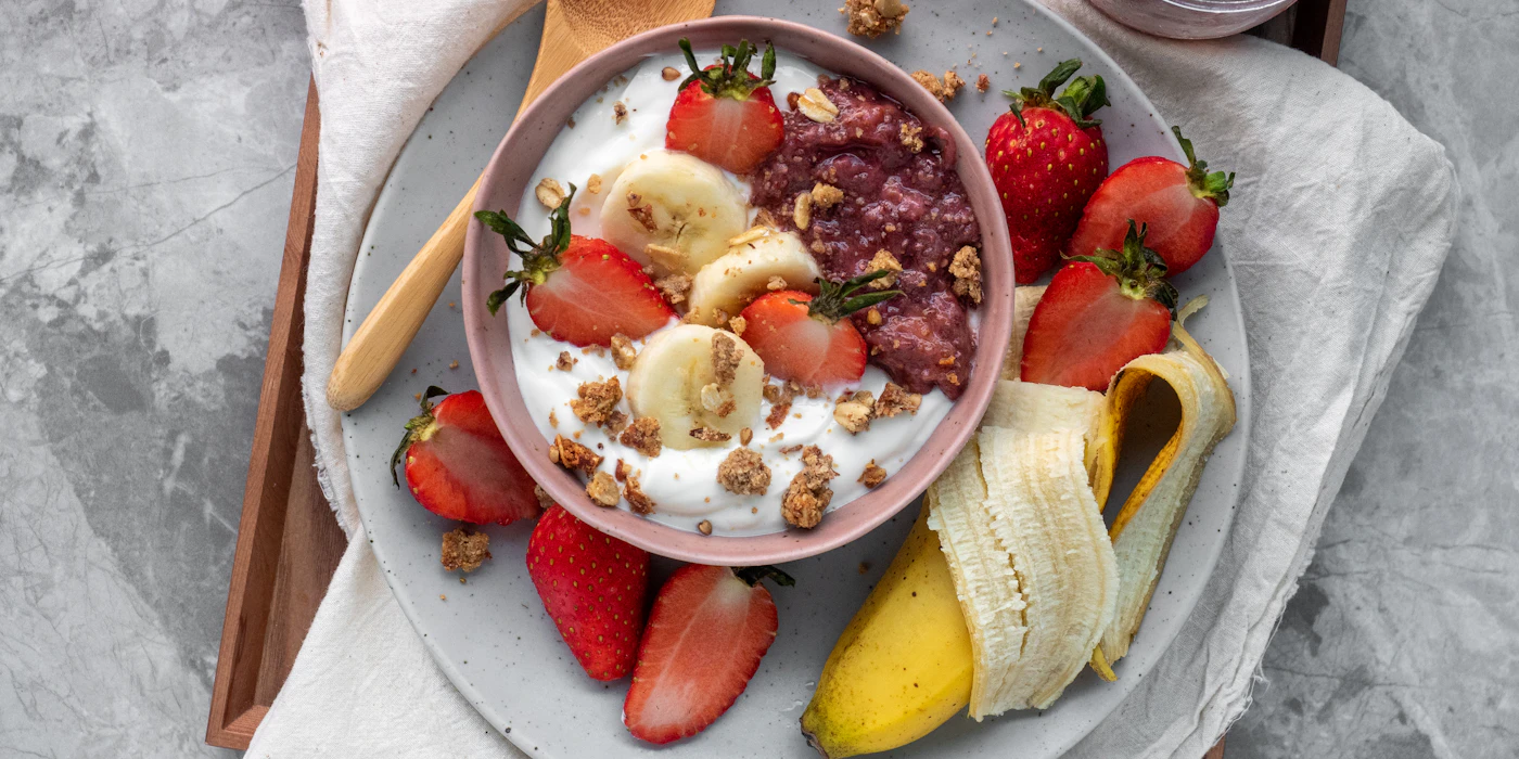 A bowl of yogurt topped with berries on a wooden table