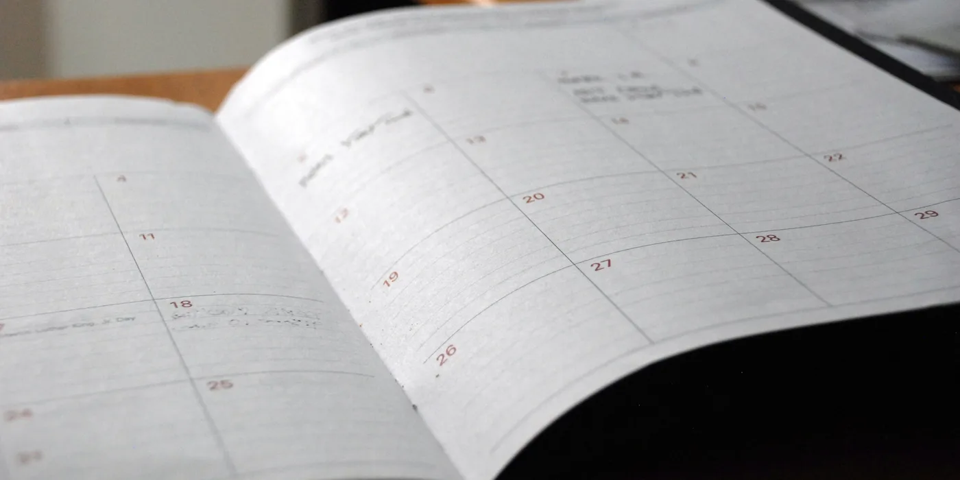 An open planner and calendar on a wooden desk