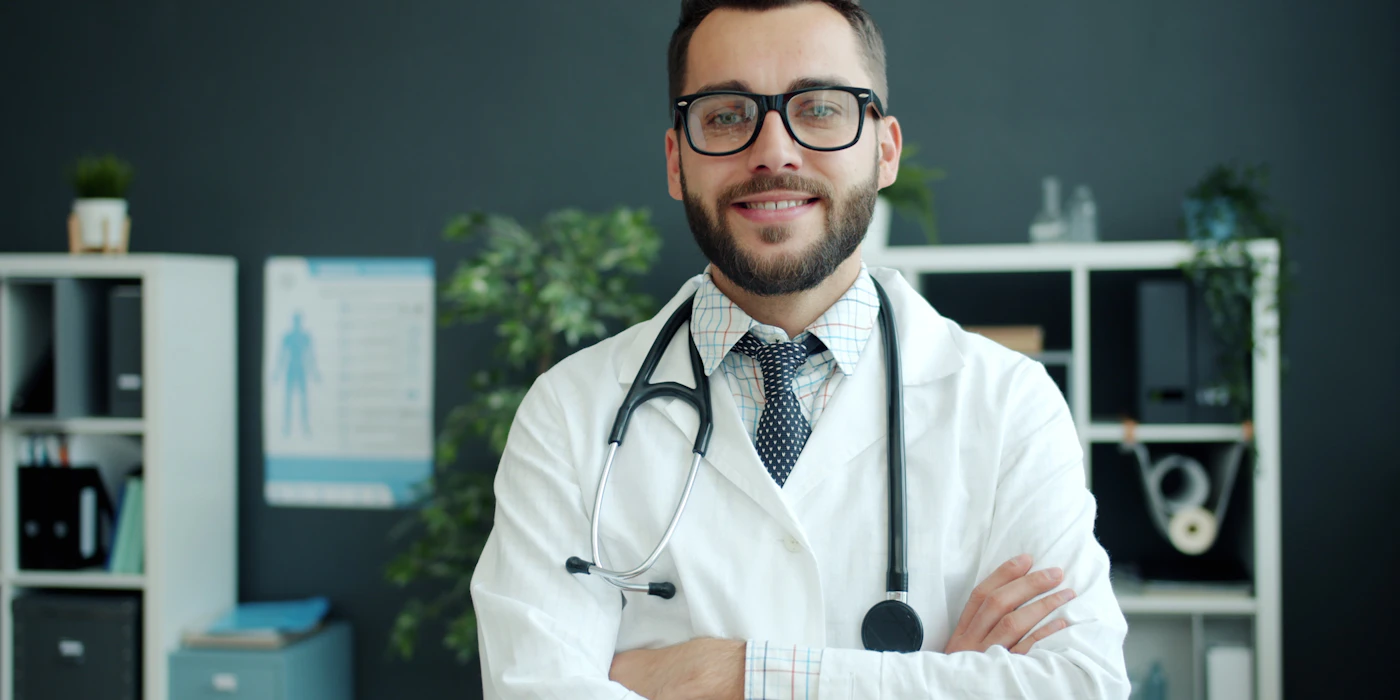 A doctor in a clinic, arms crossed, looking at the camera