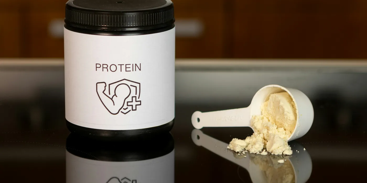 A jar of protein powder beside a measuring scoop