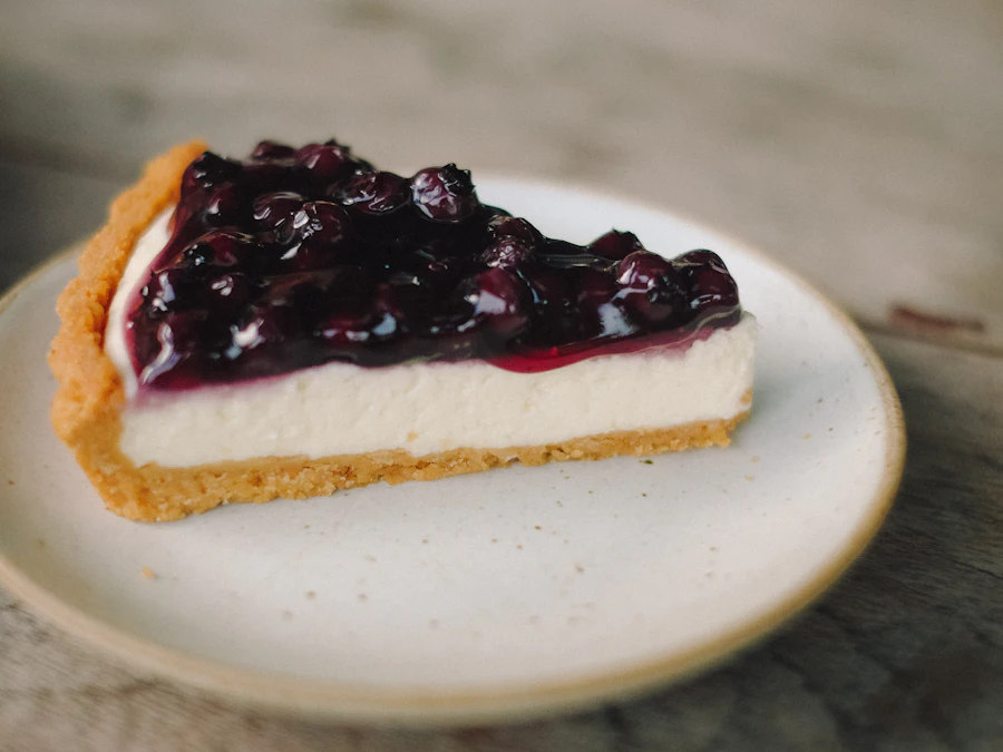 A slice of blueberry cheesecake on a ceramic plate
