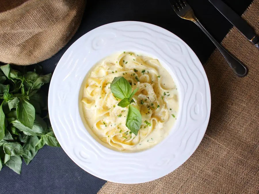 A plate of creamy fettuccine alfredo topped with basil